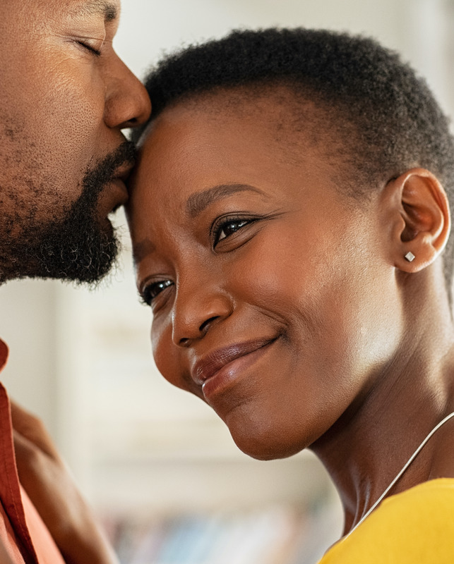Photo of a husband kissing his wife on the forehead