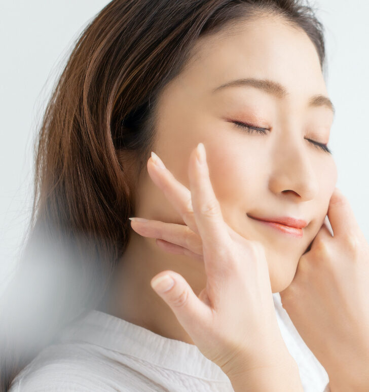 Photo of a woman with great skin touching her face
