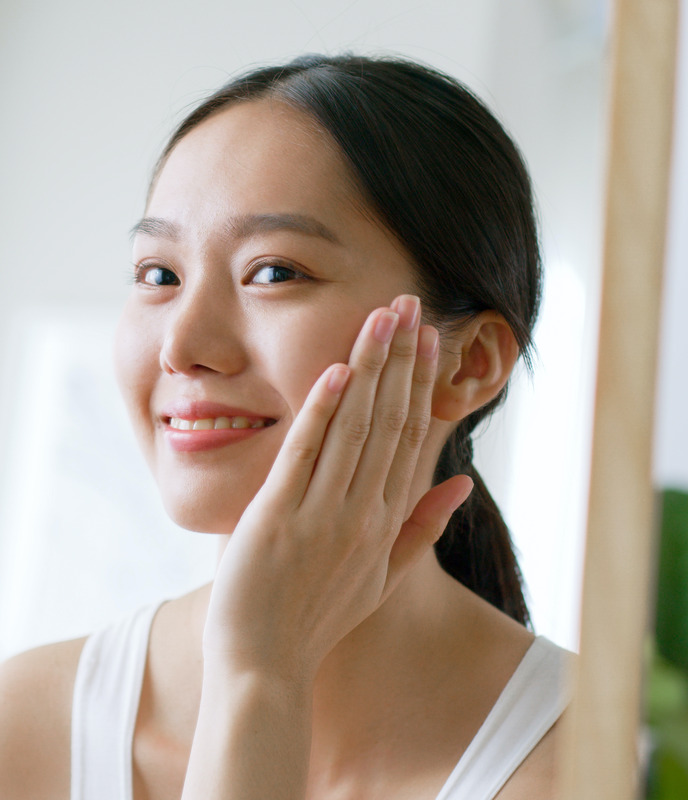 Photo of a young woman with great skin touching her face